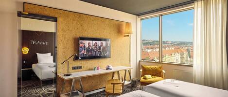 Habitación de hotel con cama, escritorio, silla, televisor y ventana con vista a la ciudad.