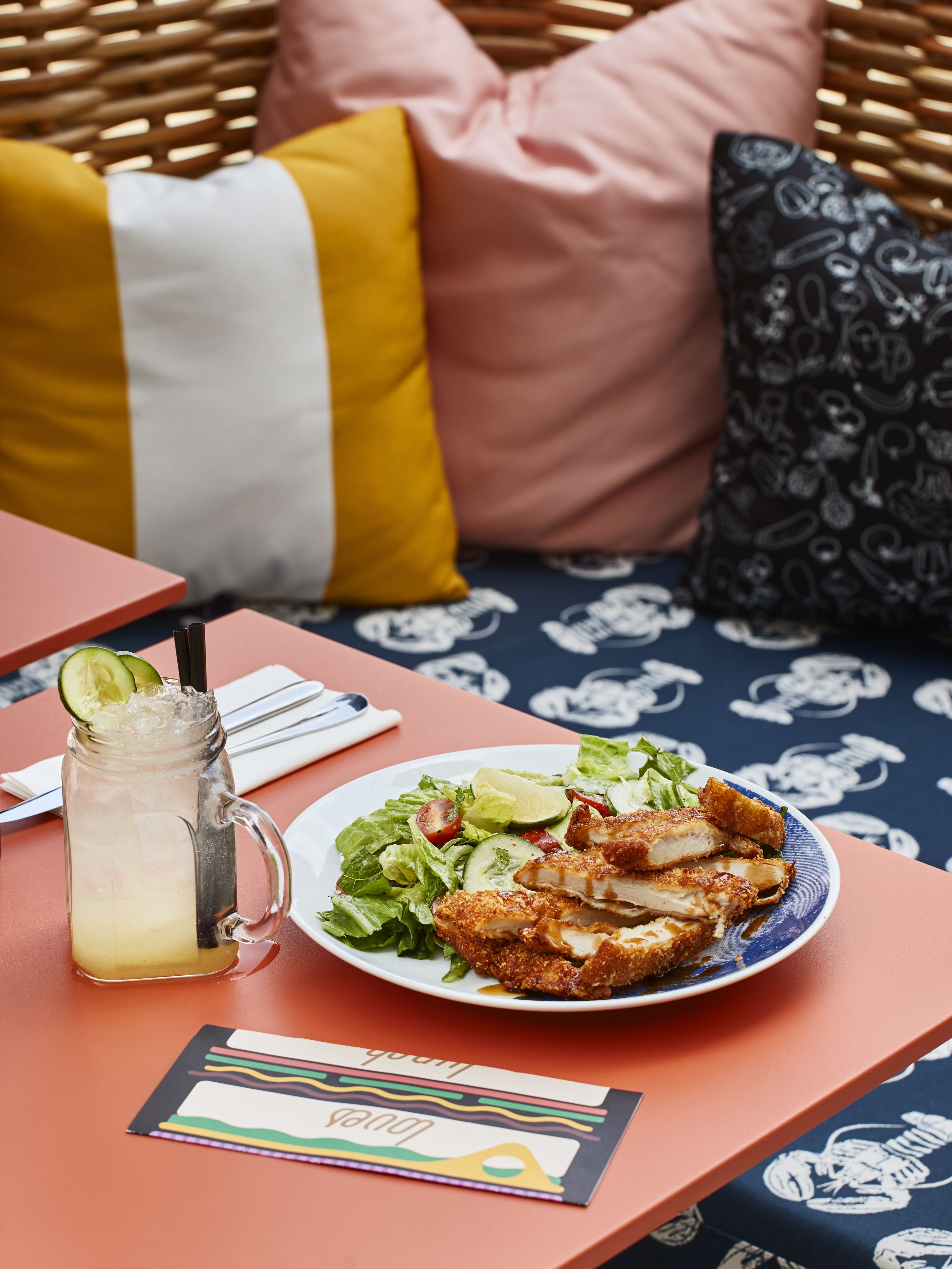 A table with a meal, a drink, and a menu.
