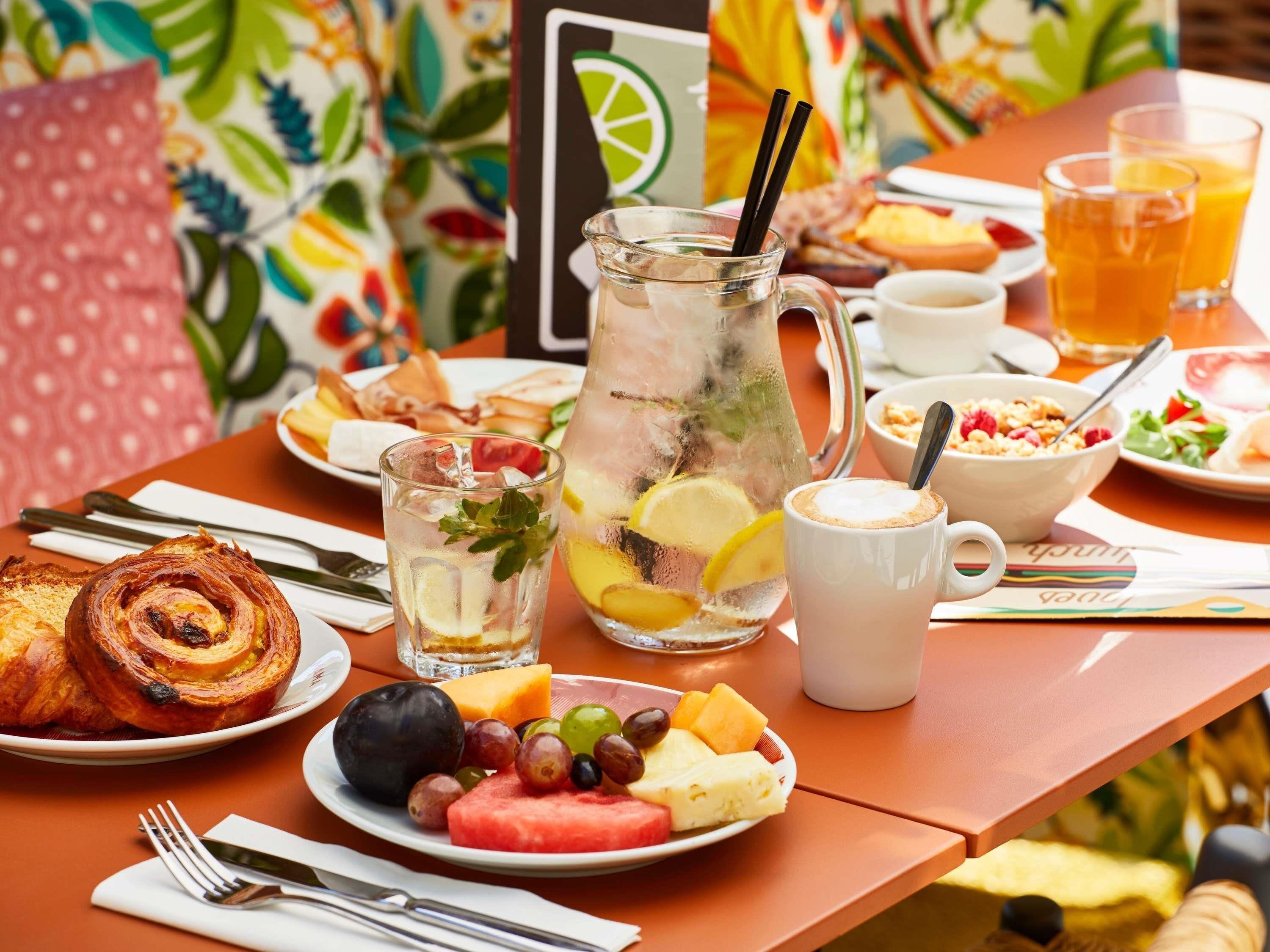 A breakfast table with croissants, fruit, a pitcher of iced tea, and a coffee cup.