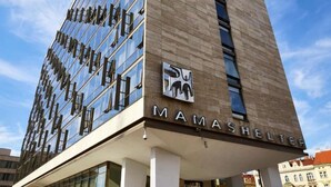 En modern byggnad med en glasfasad och en skylt med texten ”MAMASHELTER”.