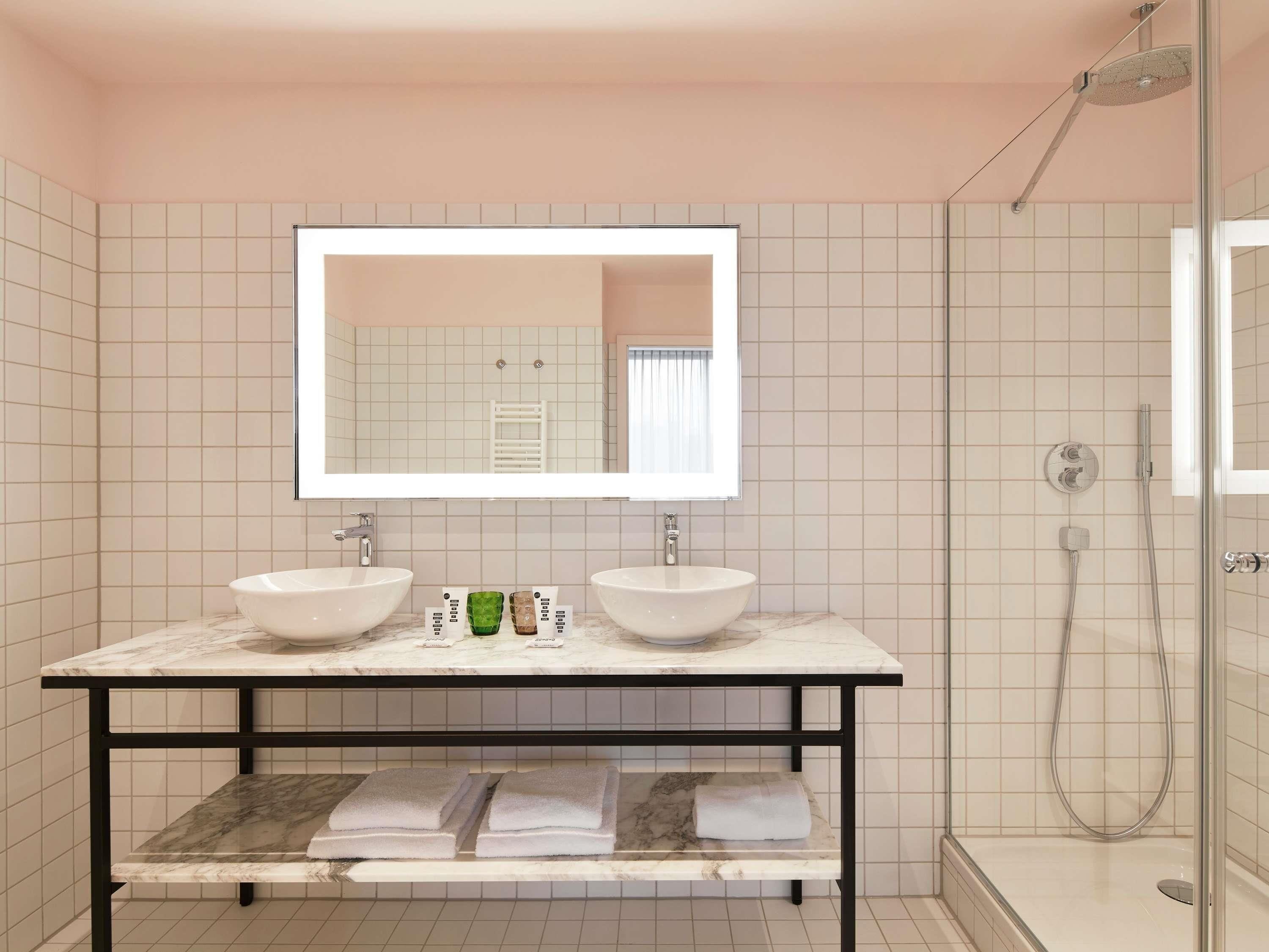 A bathroom with two sinks, a mirror, a shower, and a towel rack.