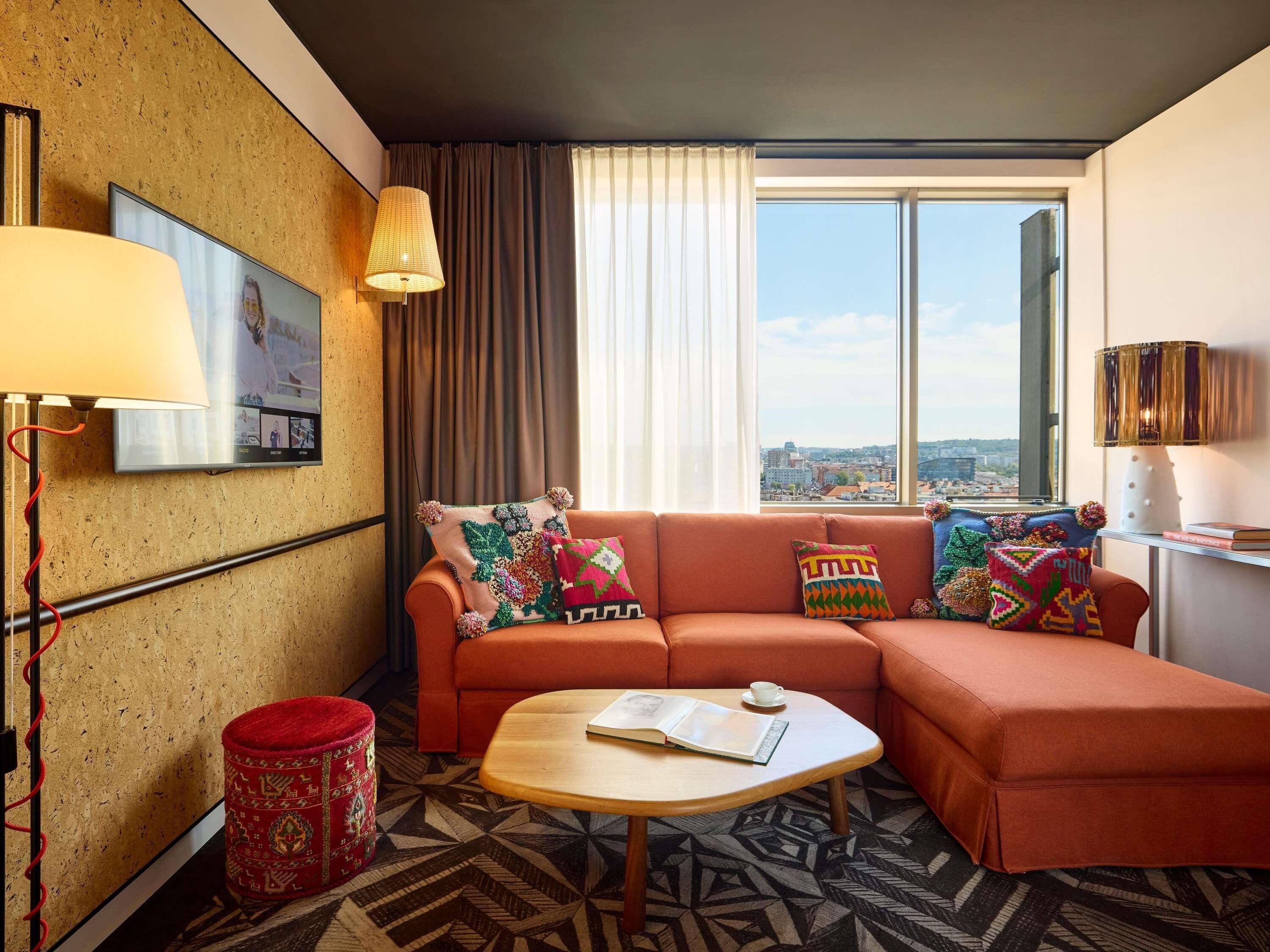 Un salon moderne avec un canapé, une table basse et une vue sur la ville grâce à de grandes fenêtres.