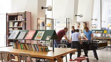 A modern library with bookshelves, a reading area, and a foosball table.