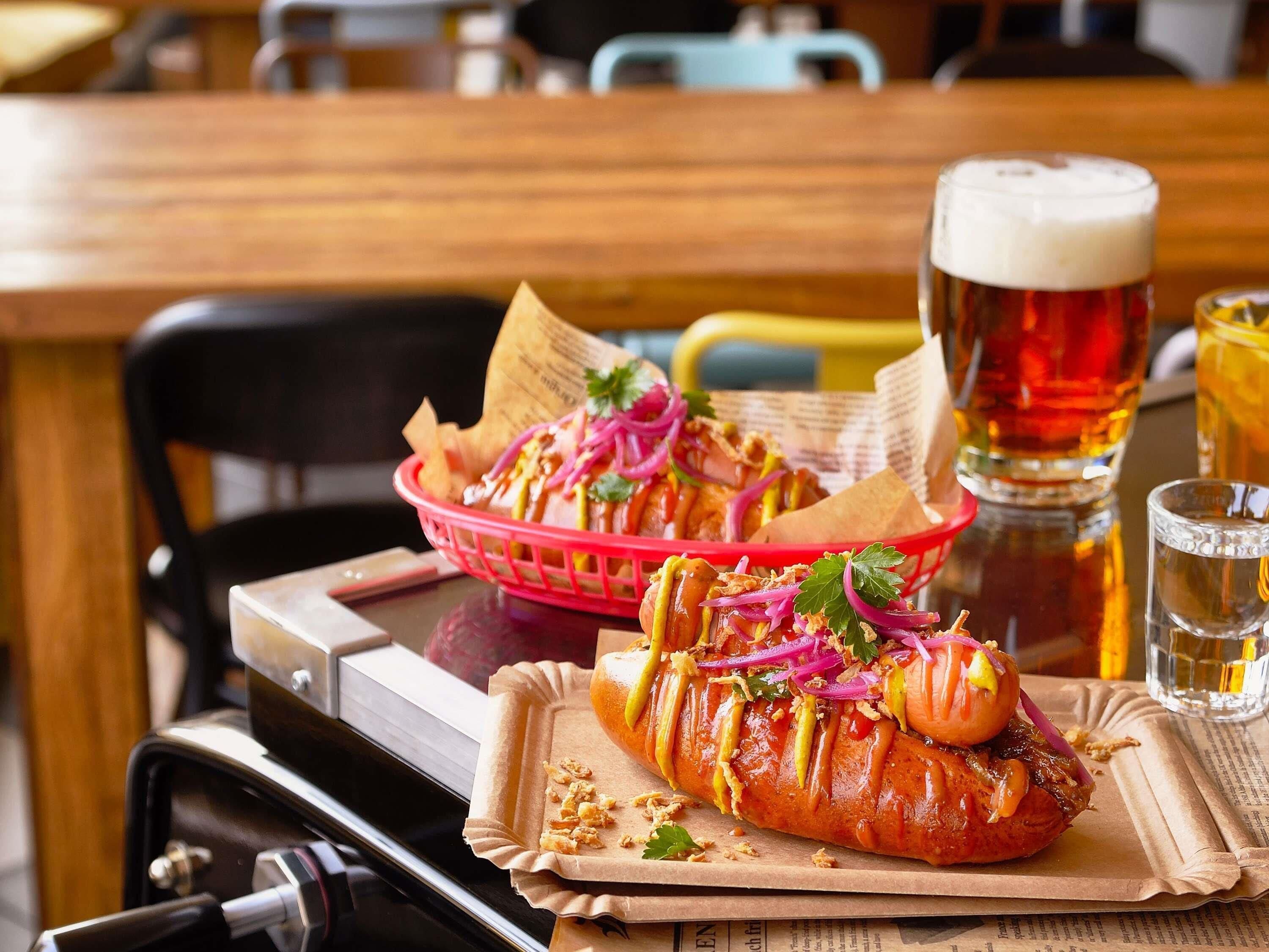 A dining table with a basket of food, a beer mug, and a glass of beer.
