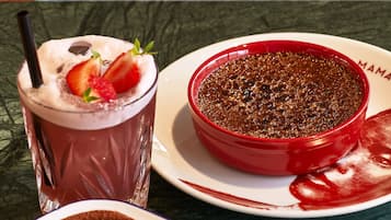 A dessert tray with a chocolate dessert, a glass of chocolate drink, and a plate with chocolate powder.