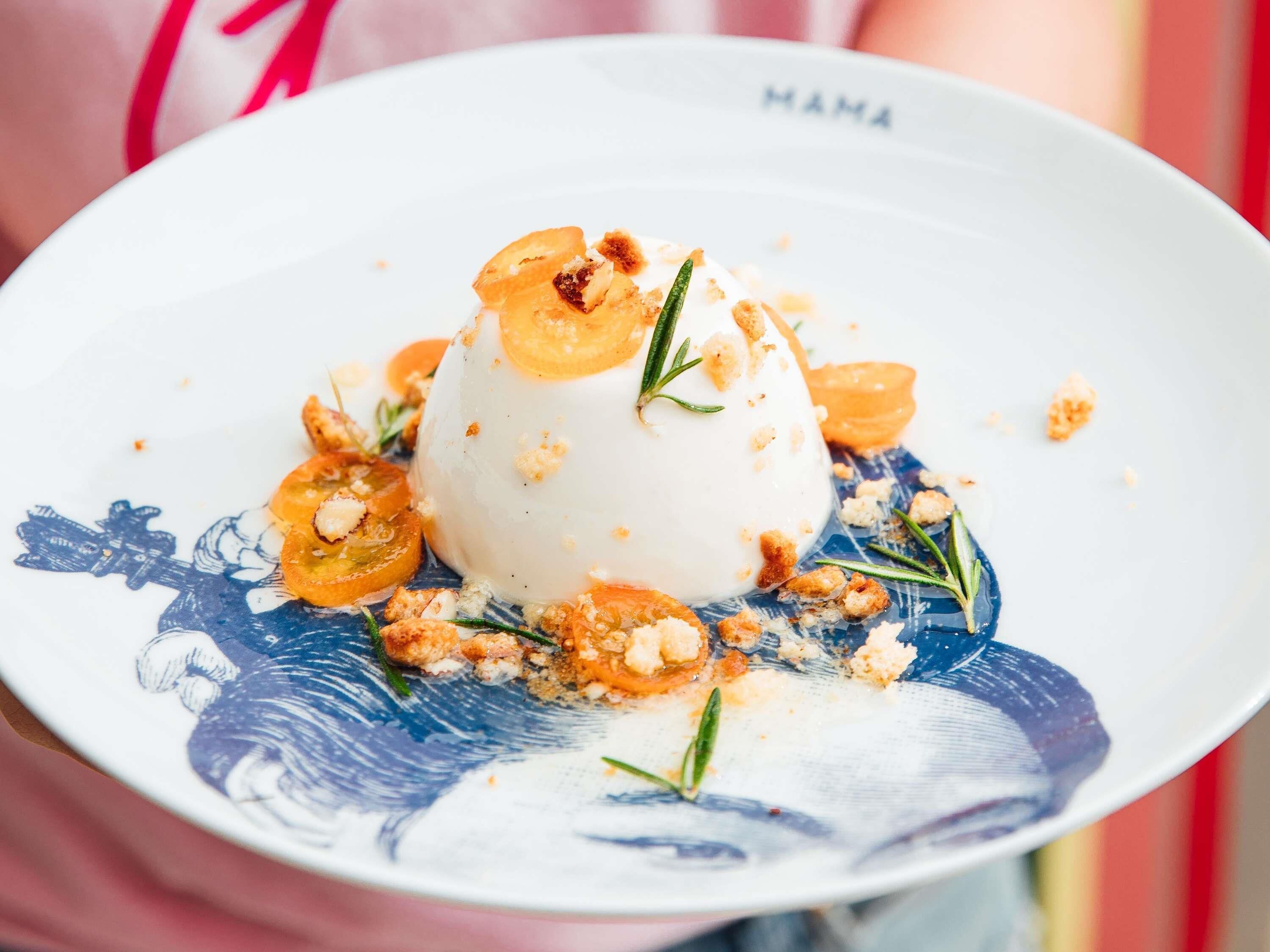 Un dessert présenté dans une assiette à motifs bleus, agrémenté d’une branche qui ressemble à du romarin.