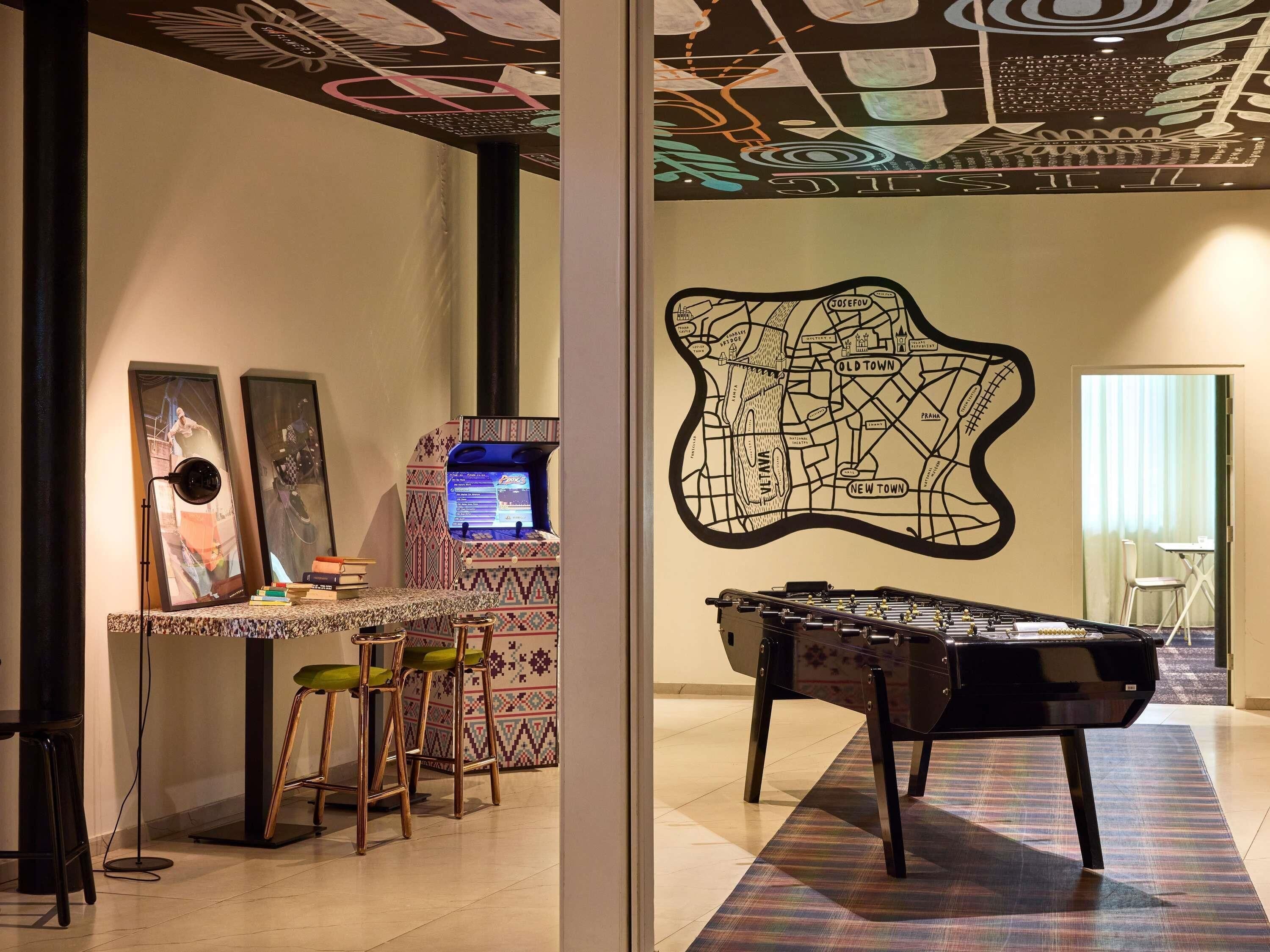 Una habitación con mesa de fútbol de mesa, una zona de bar con taburetes y una pared con un mural de mapa.