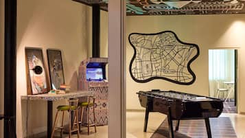Una habitación con mesa de fútbol de mesa, una zona de bar con taburetes y una pared con un mural de mapa.