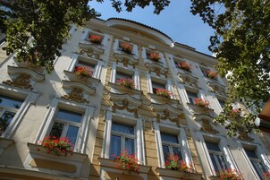 Um edifício de vários andares com detalhes arquitetônicos elaborados, incluindo molduras decorativas e caixilhos de janela.