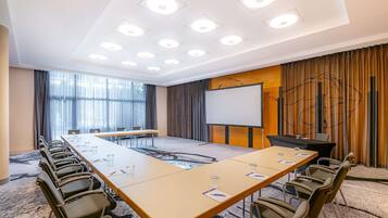 A conference room with a long table, chairs, a projector screen, and a whiteboard.