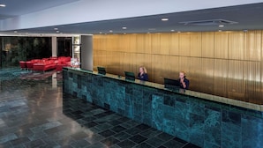 A reception area with a marble reception desk, red seating, and a modern wall design. - NH Prague City (Prague)