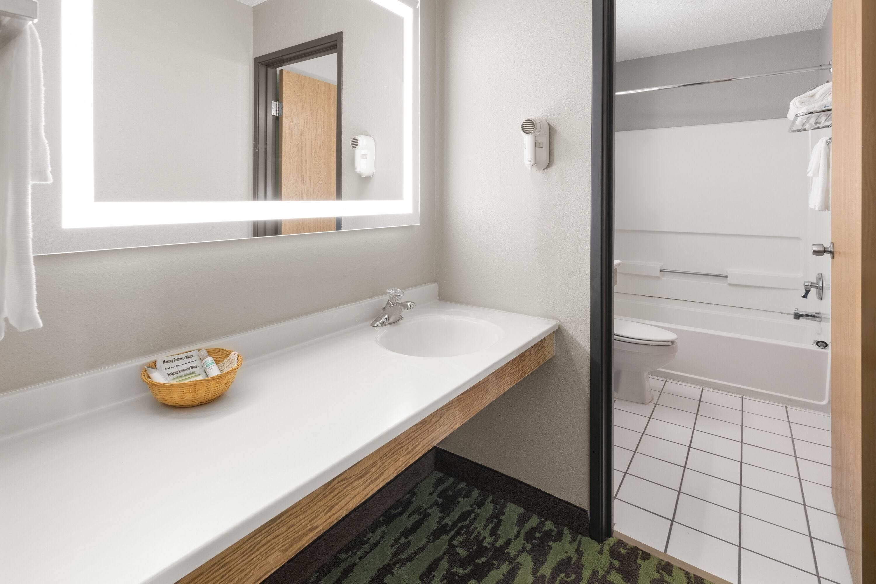 Un baño con lavamanos blanco, espejo y zona de ducha.