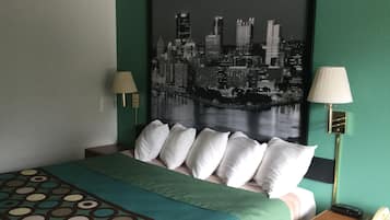 Hotelkamer met een bed, groene wanden, een stadsgezicht schilderij, twee bedlampen en een telefoon op een houten nachtkastje.