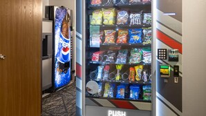 Una máquina expendedora de aperitivos y un refrigerador de Pepsi en un pasillo de hotel.