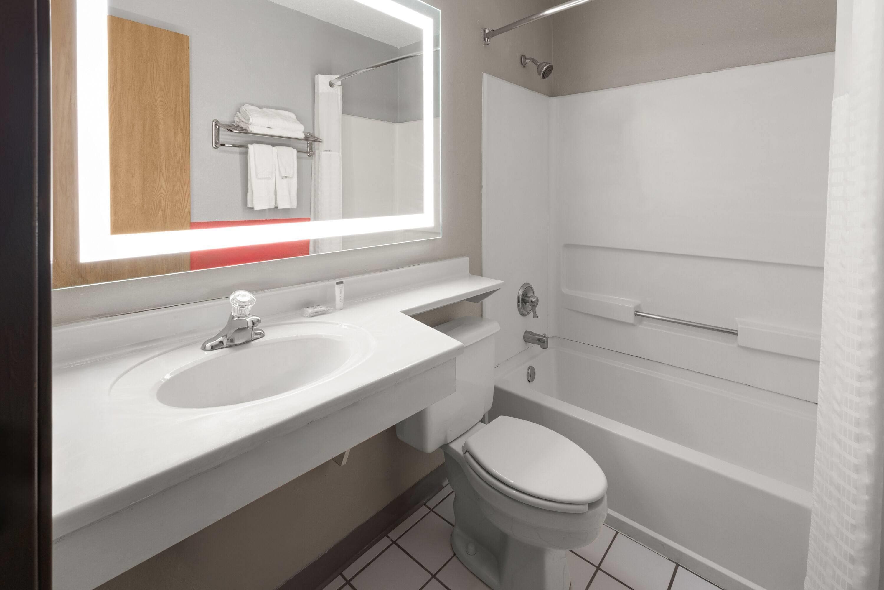 Une salle de bain moderne avec un lavabo blanc, un miroir et des toilettes.