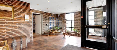 A lobby with a brick wall, a reception desk, a bench, and a door with a window.