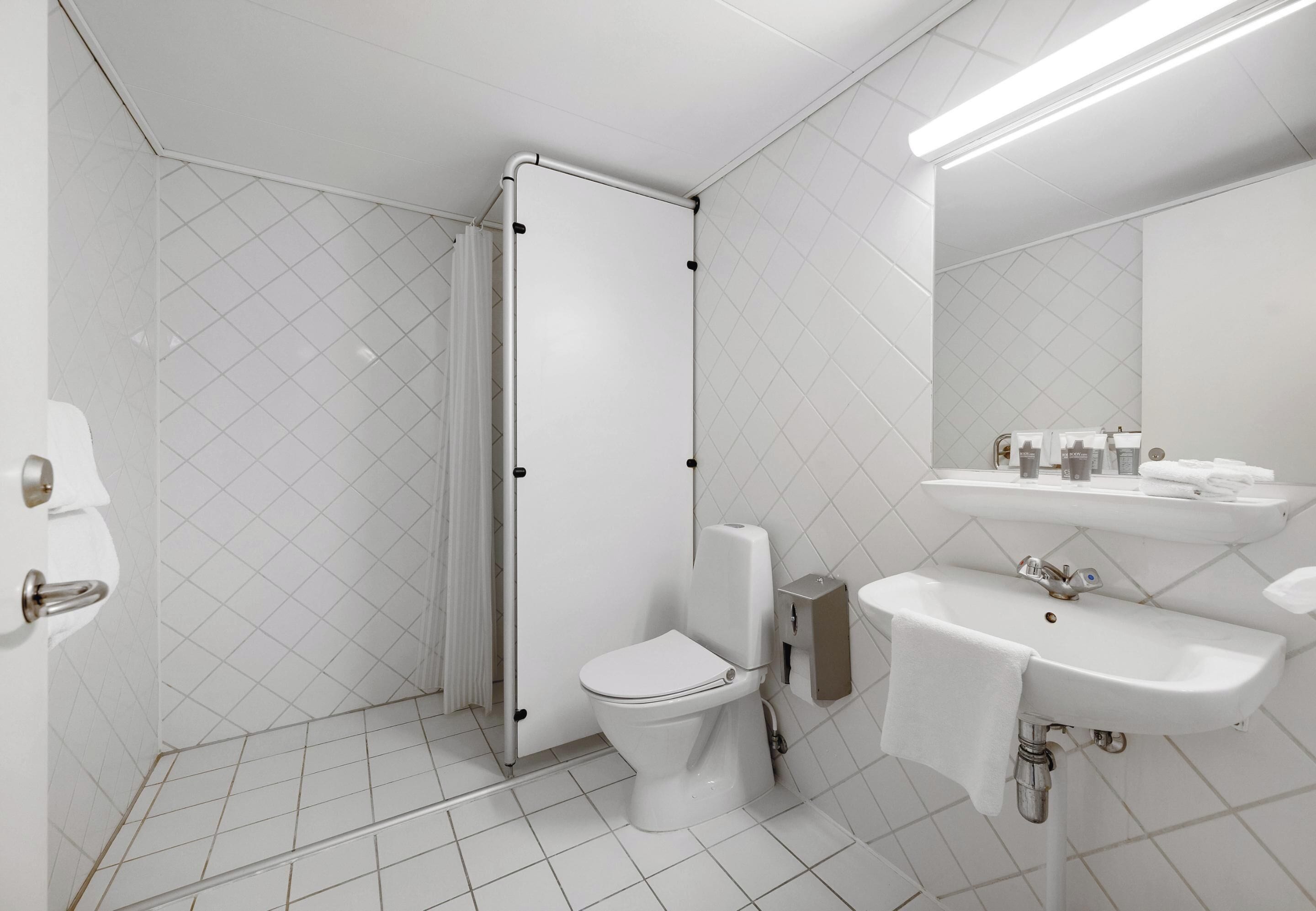 A modern bathroom with a toilet, shower, and sink.