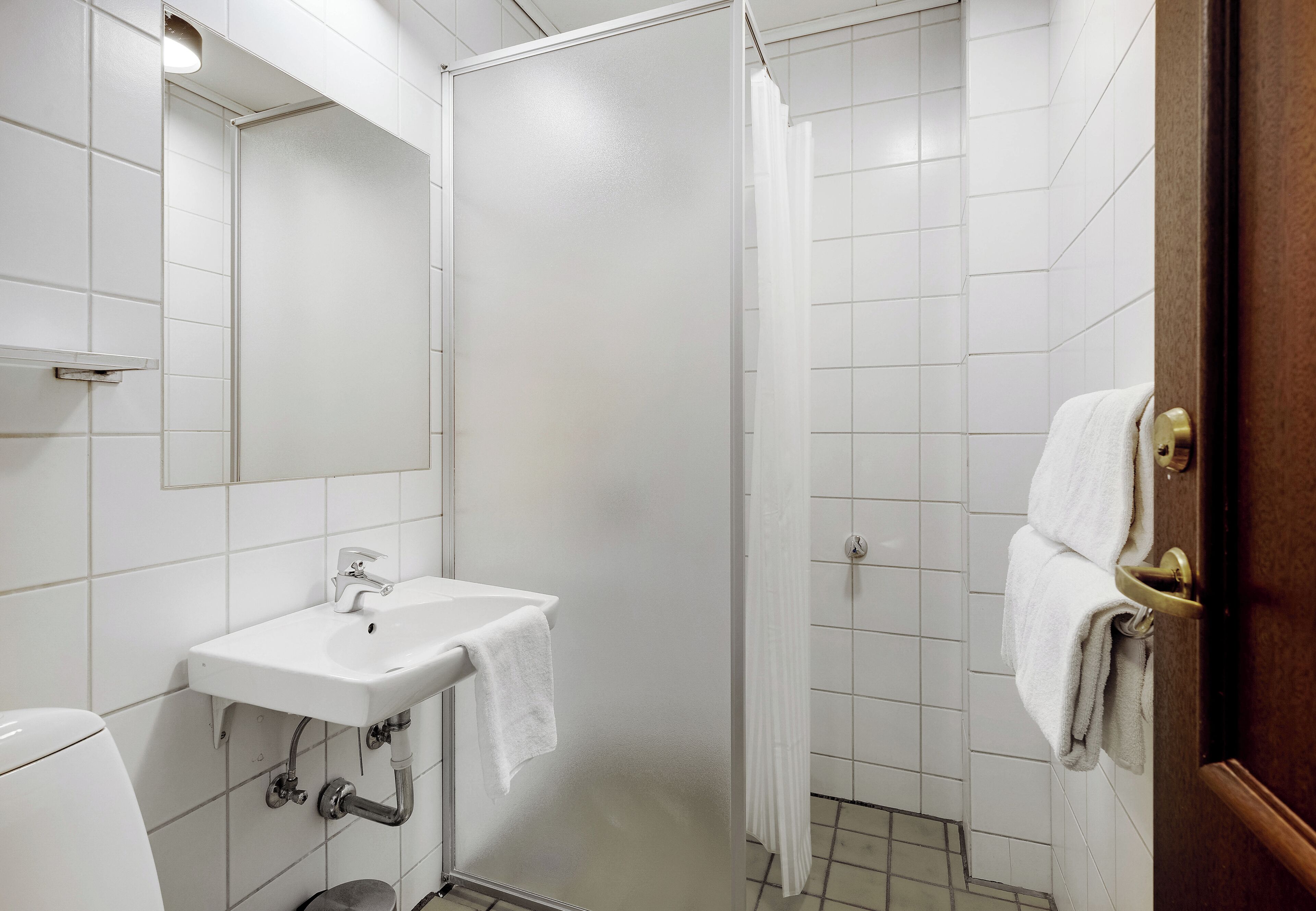 A bathroom with a white sink, mirror, and shower curtain.