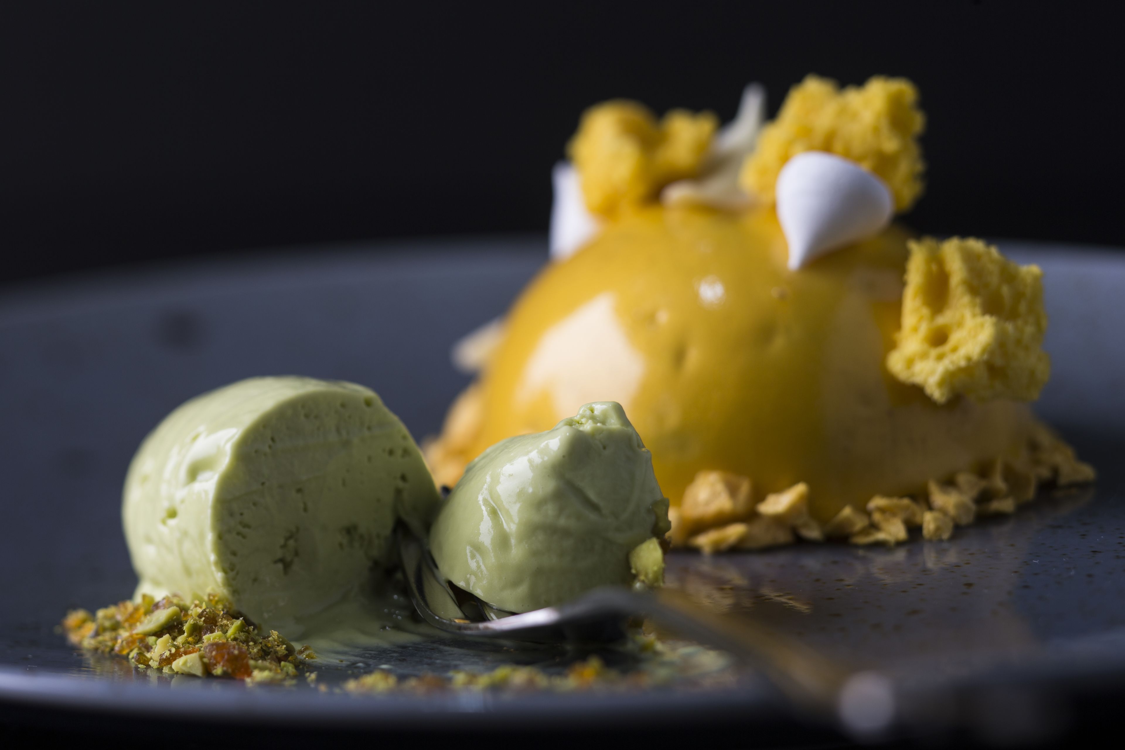 A dessert with a scoop of green ice cream and a caramelized dessert on a plate.