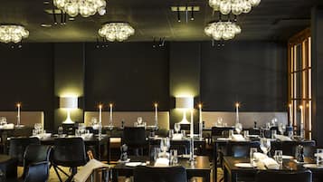 A restaurant with multiple tables set for dining, each with candles and wine glasses.