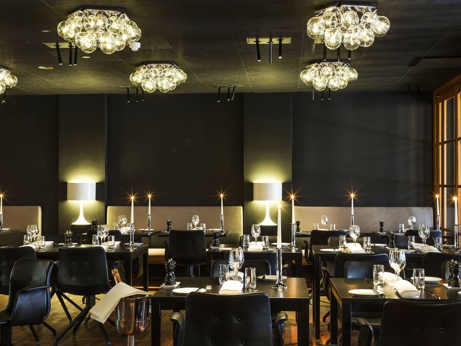 A restaurant with multiple tables set for dining, each with candles and wine glasses.