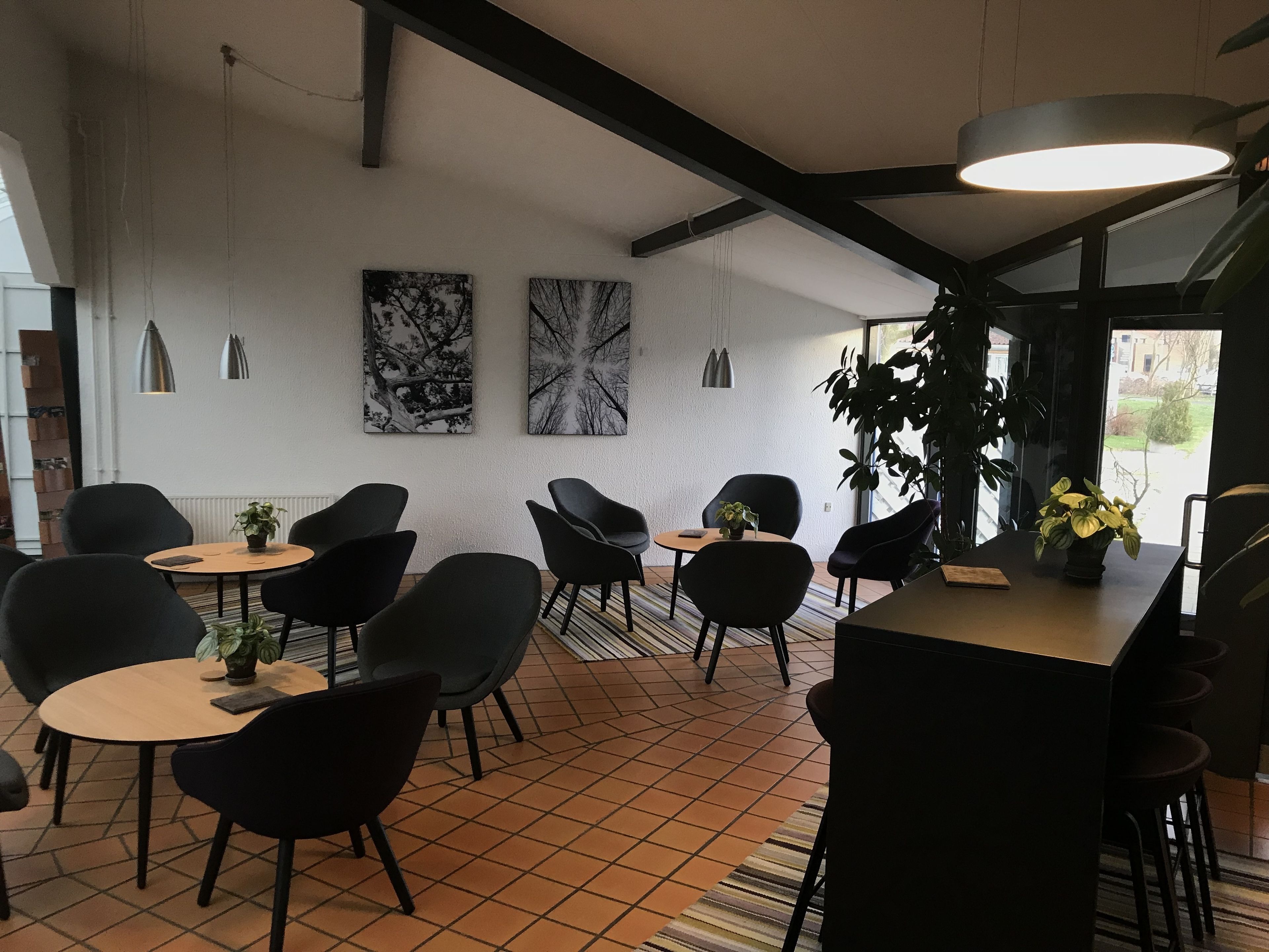 A modern interior with black chairs, round tables, and artwork on the walls.
