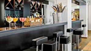 A modern bar area with a dark counter, bar stools, and a variety of bottles and glasses. - Best Western Hotel Hillerod (Hillerod)