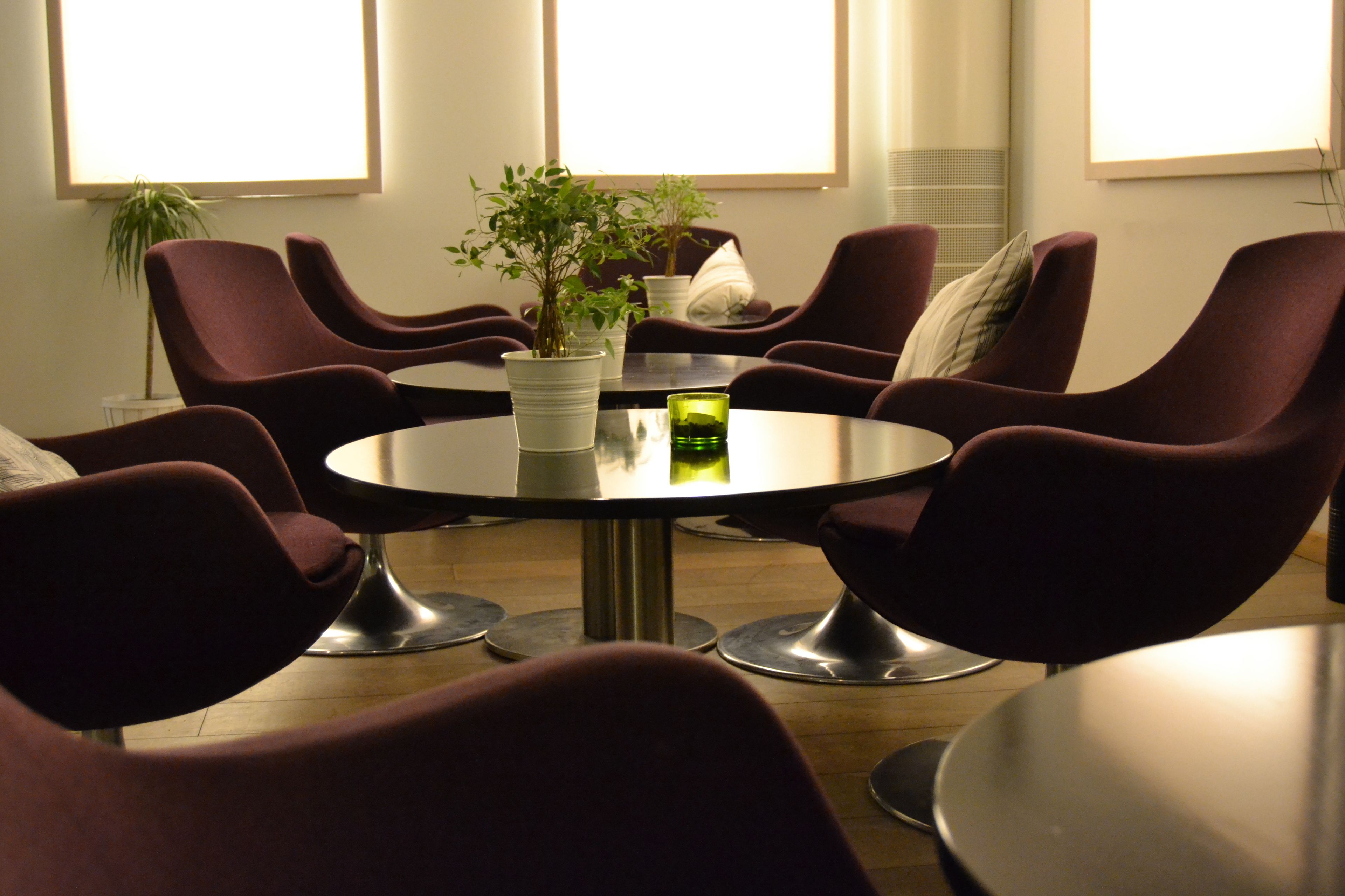 A conference room with round tables and purple chairs, potted plants, and a green candle on the tables.