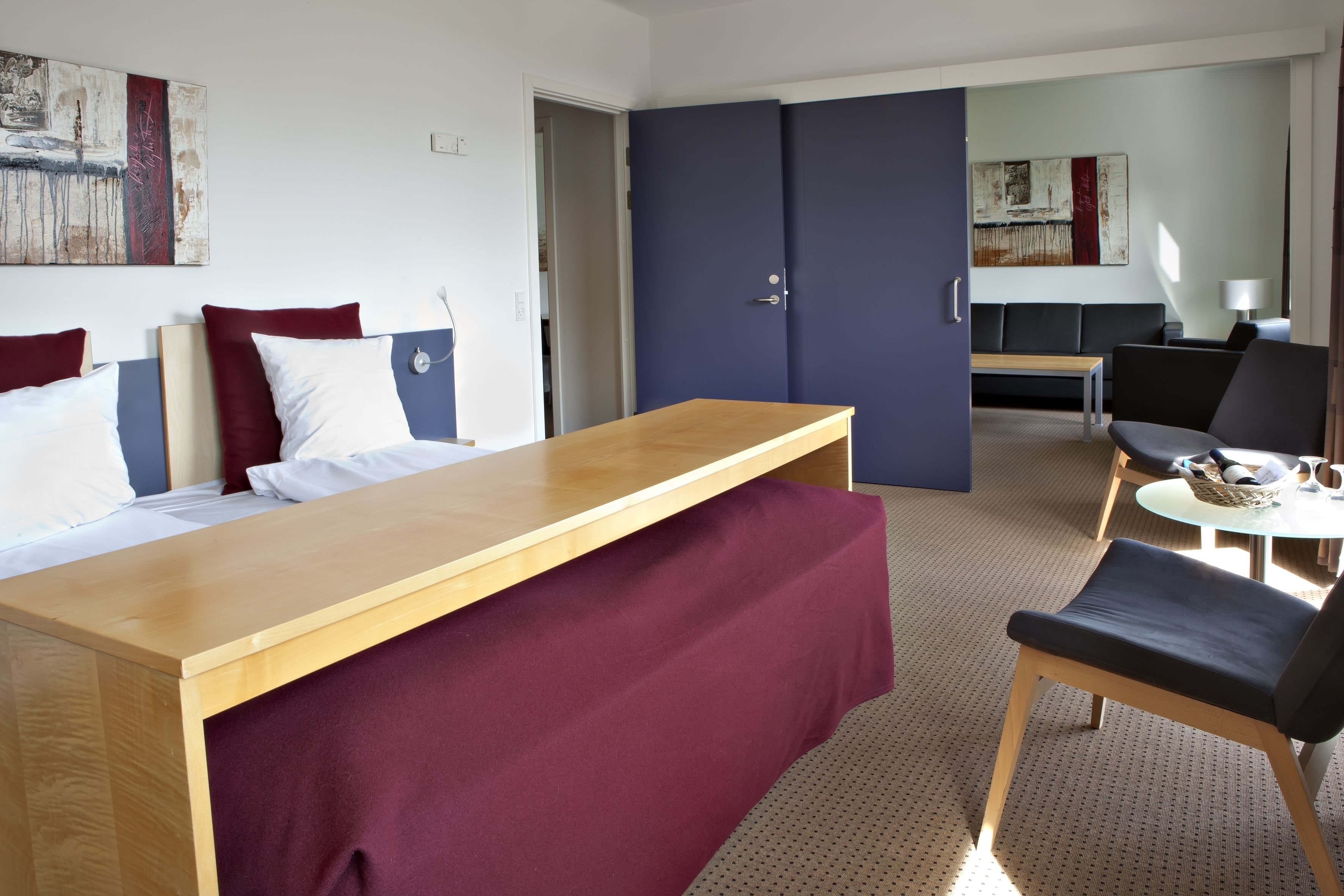 A hotel room with a bed, a desk, a chair, a sofa, and a dining table.