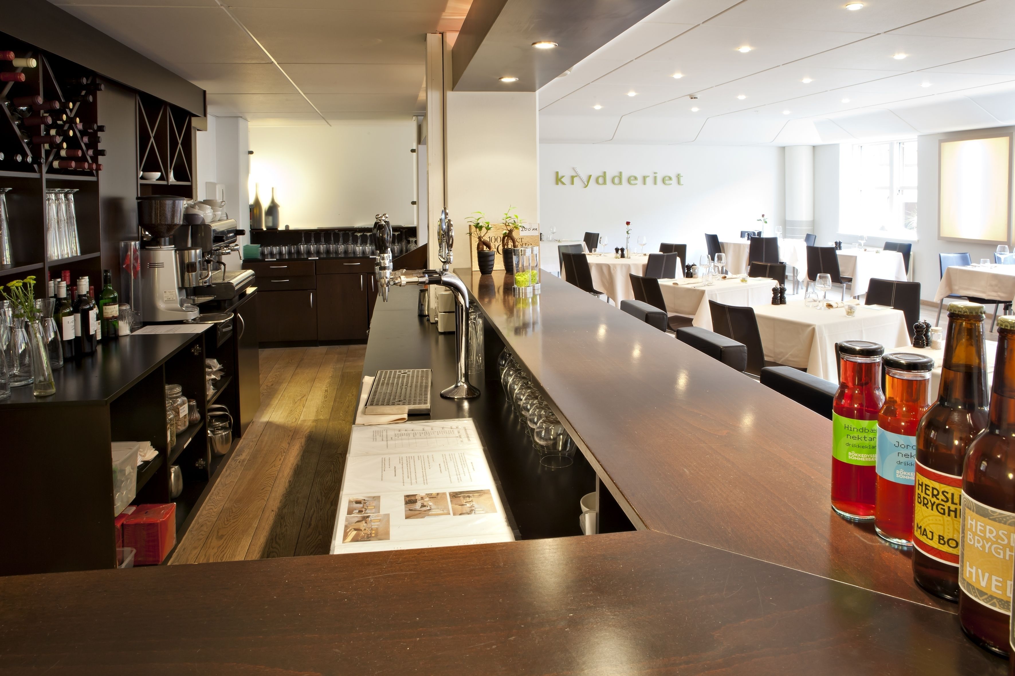 A modern bar area with a long counter, wine bottles, and a menu.