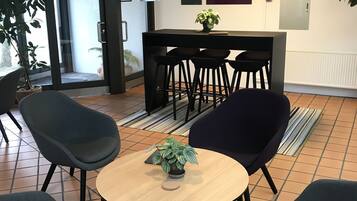 A modern interior with a round table, four chairs, a potted plant, and a bar area with stools.