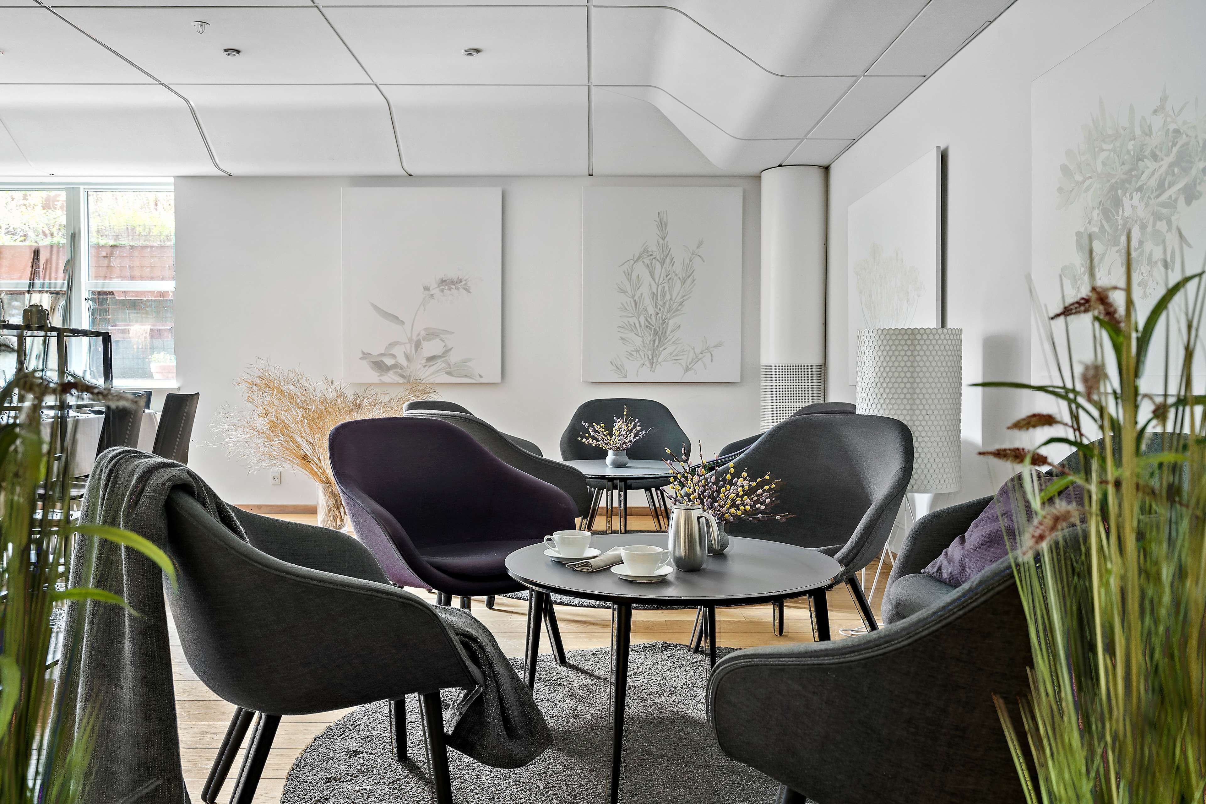A modern meeting room with a round table, black and purple chairs, and minimalist decor.