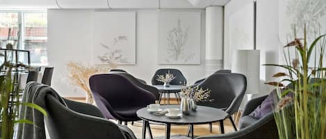 Una sala de reuniones moderna con una mesa redonda, sillas negras y púrpuras, y una decoración minimalista.
