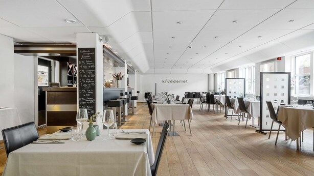A modern restaurant interior with multiple tables, a chalkboard menu, and a view of the outside through large windows. - Best Western Hotel Hillerod (Hillerod)
