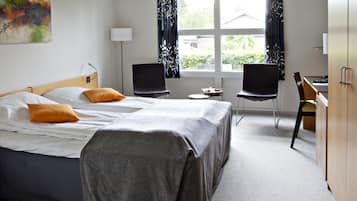 A hotel room with two beds, a desk, and a chair.