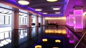 Un moderno vestíbulo de hotel con piso reflectante, ventanas amplias y una zona de recepción con iluminación morada.