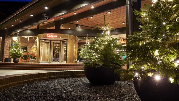 Un edificio con un letrero que dice 'Casino', un árbol de Navidad y una planta en maceta al frente.