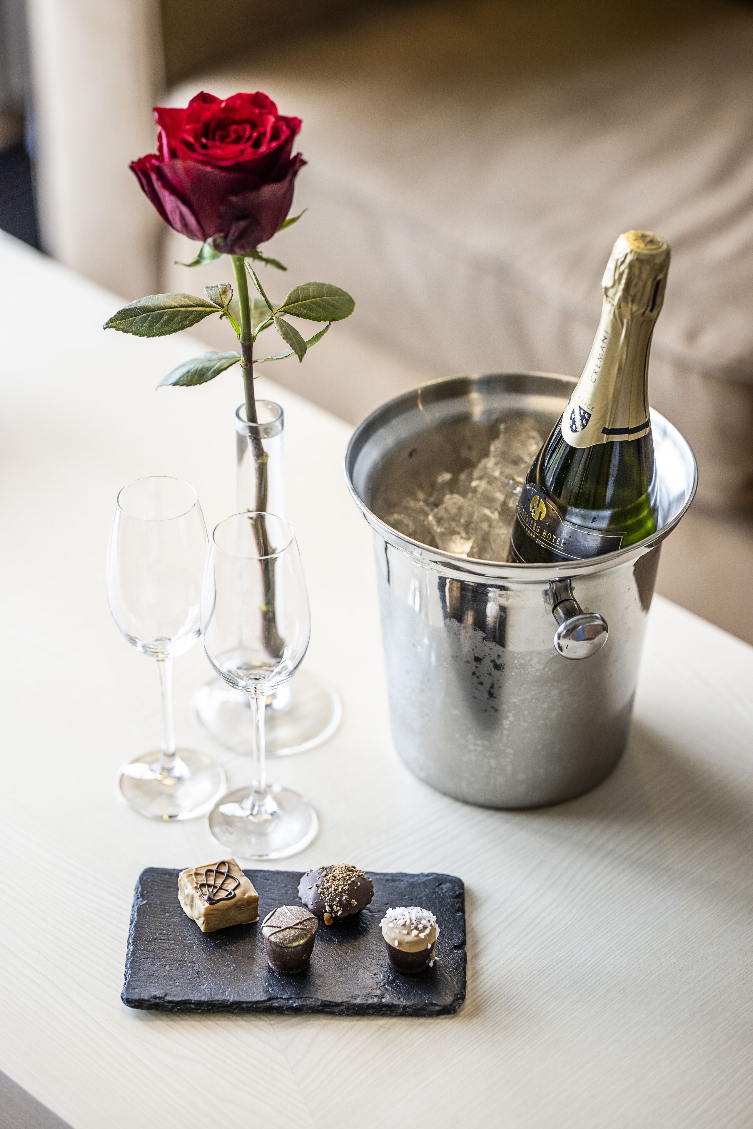 Una bottiglia di champagne in un secchio di metallo con due bicchieri da vino vuoti e una rosa.
