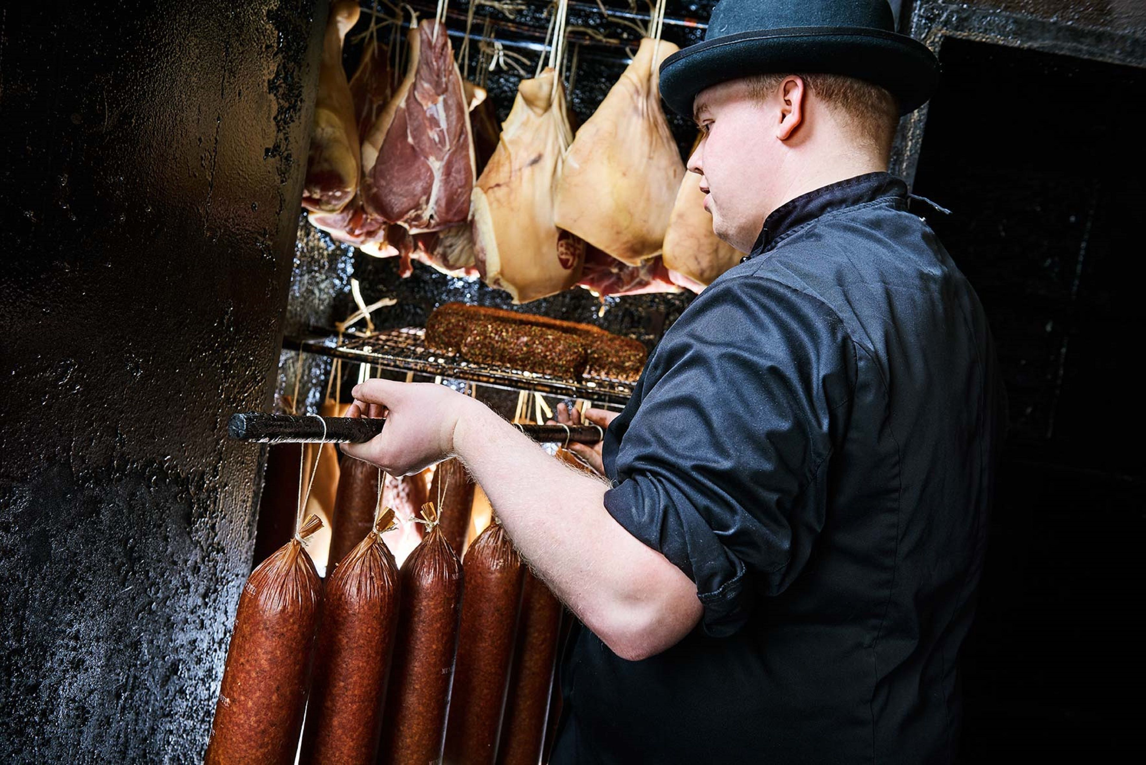 Iemand die vleeswaren bereidt in een keuken.