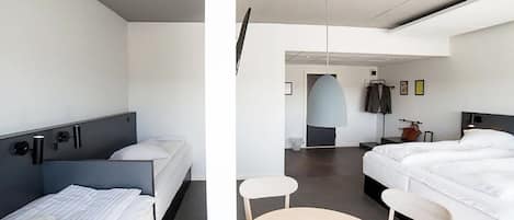 Camera d'albergo moderna con due letti, un tavolino e una televisione.