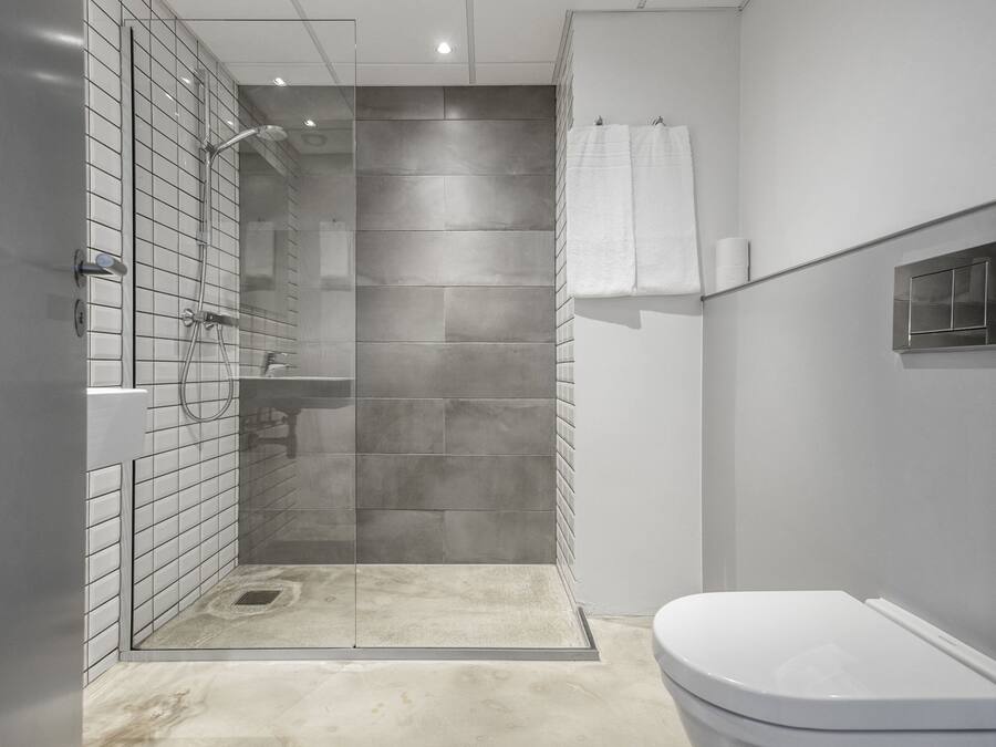 Un baño moderno con ducha de vidrio, inodoro blanco y piso de baldosas.