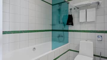 Um banheiro com box de vidro, vaso sanitário branco e porta-toalhas com toalhas dobradas.