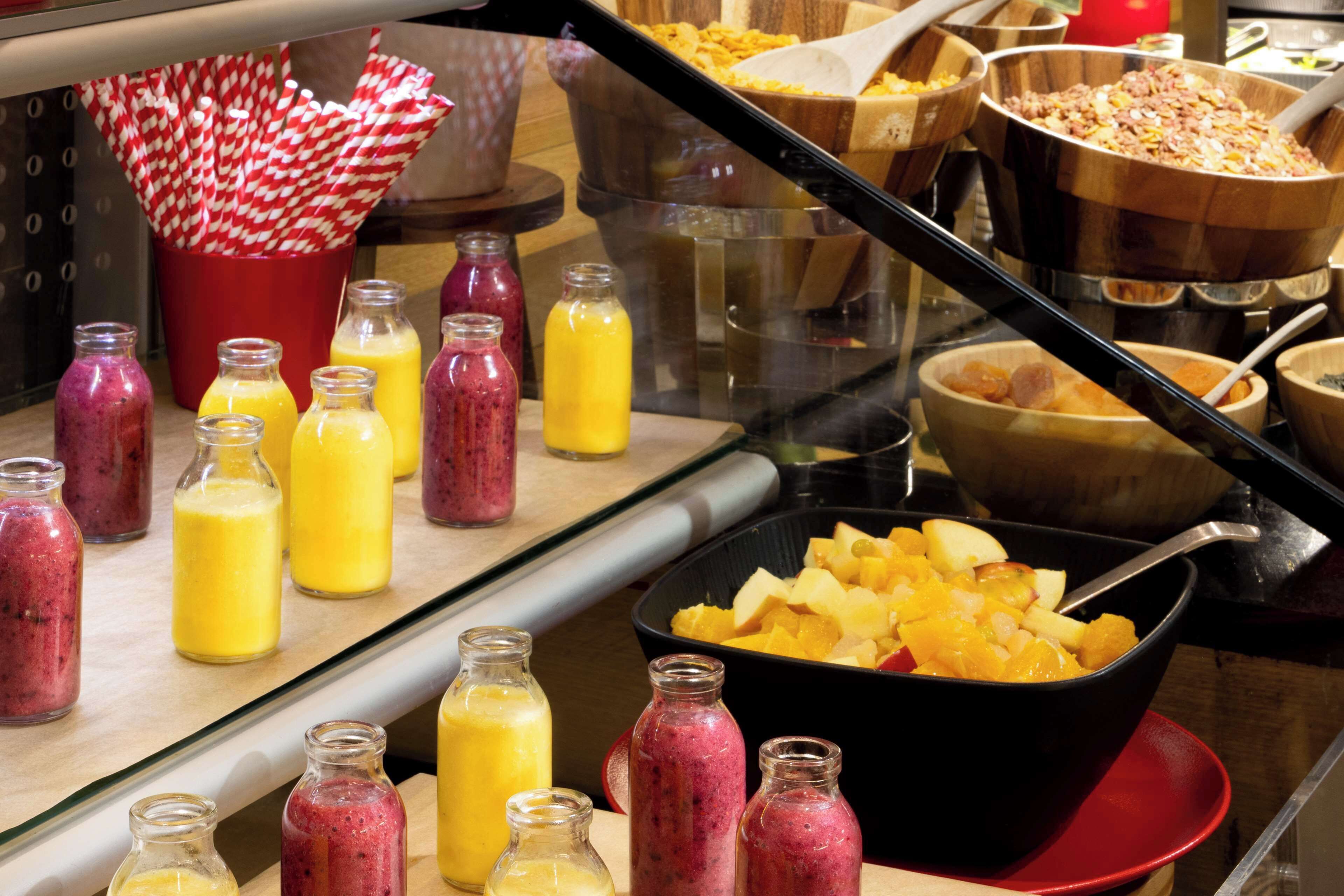 A buffet with various food items and beverages, including bowls of fruit and bottles of smoothies.