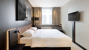 A modern hotel room with a large bed, a flat-screen TV, a desk, and a window with curtains. - Park Inn by Radisson Central Tallinn (Tallinn)