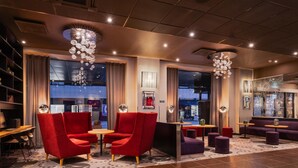 A modern hotel lobby with red armchairs, round tables, and a large chandelier. - Park Inn by Radisson Central Tallinn (Tallinn)