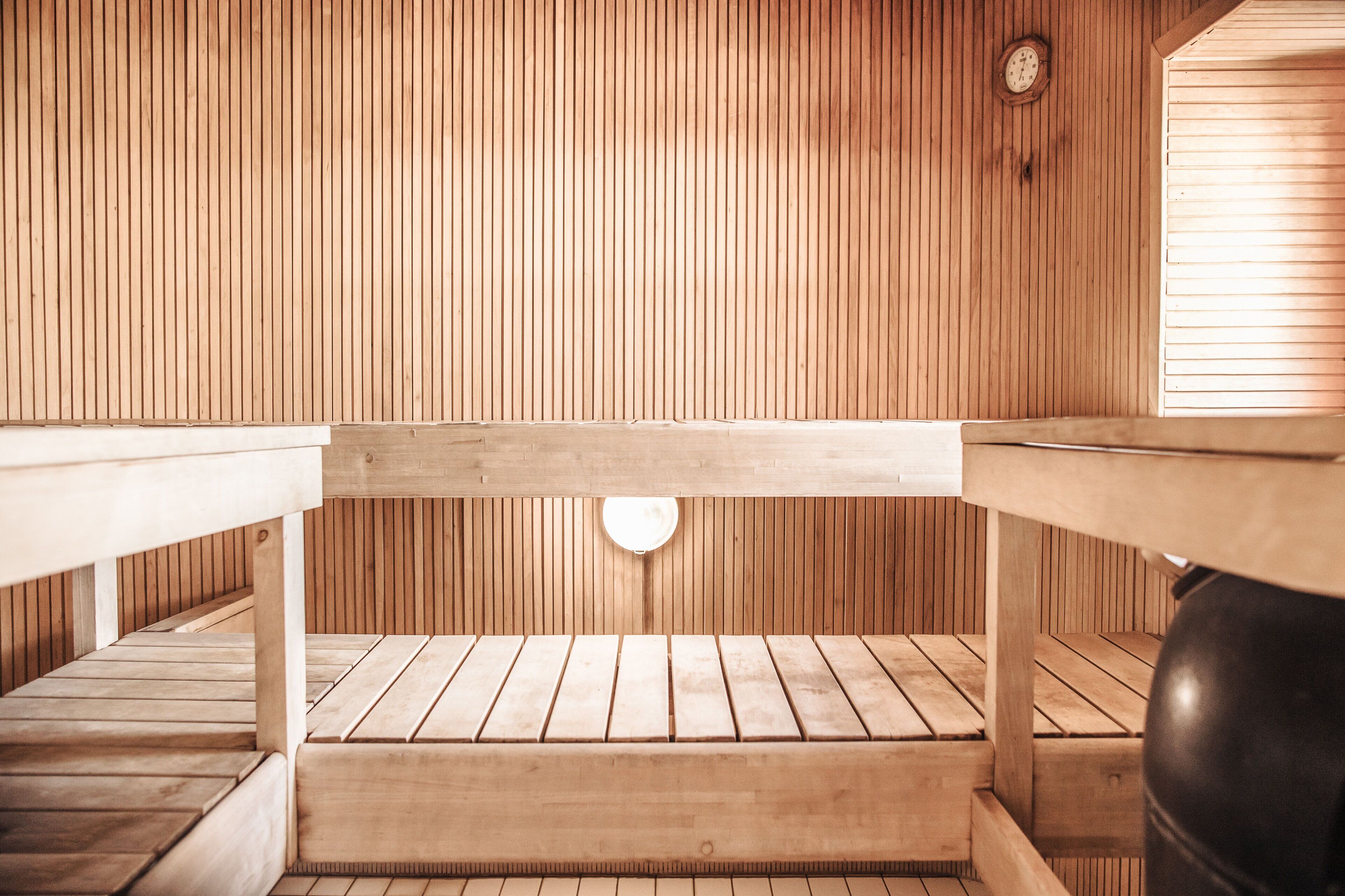 A sauna room with wooden benches and a bench in the center.