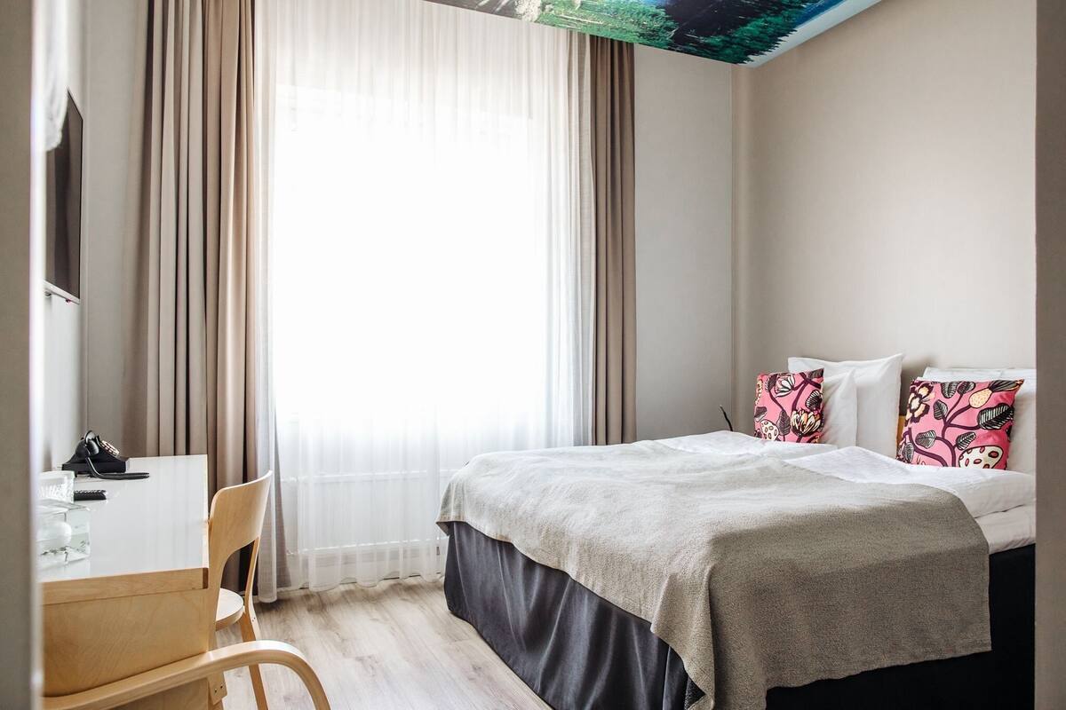 Una habitación de hotel con una cama, un escritorio y una silla.