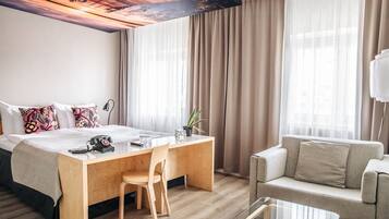 Habitación de hotel con cama, escritorio, silla, sofá y mesa de centro de vidrio.