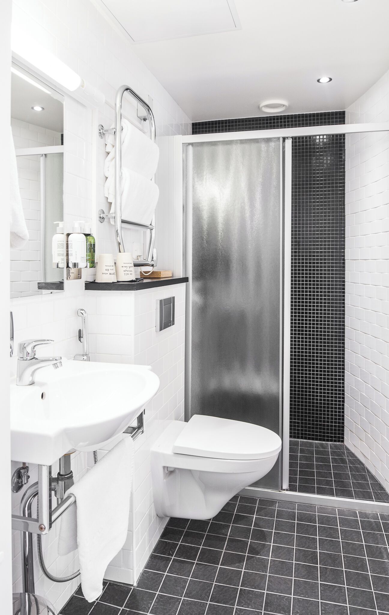 A modern bathroom with a white sink, toilet, and a glass shower enclosure.