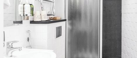 A modern bathroom with a white sink, toilet, and a glass shower enclosure.